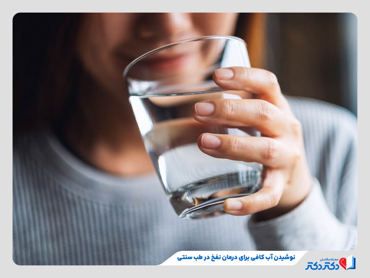 زن در حال نوشیدن آب به عنوان درمان نفخ با طب سنتی